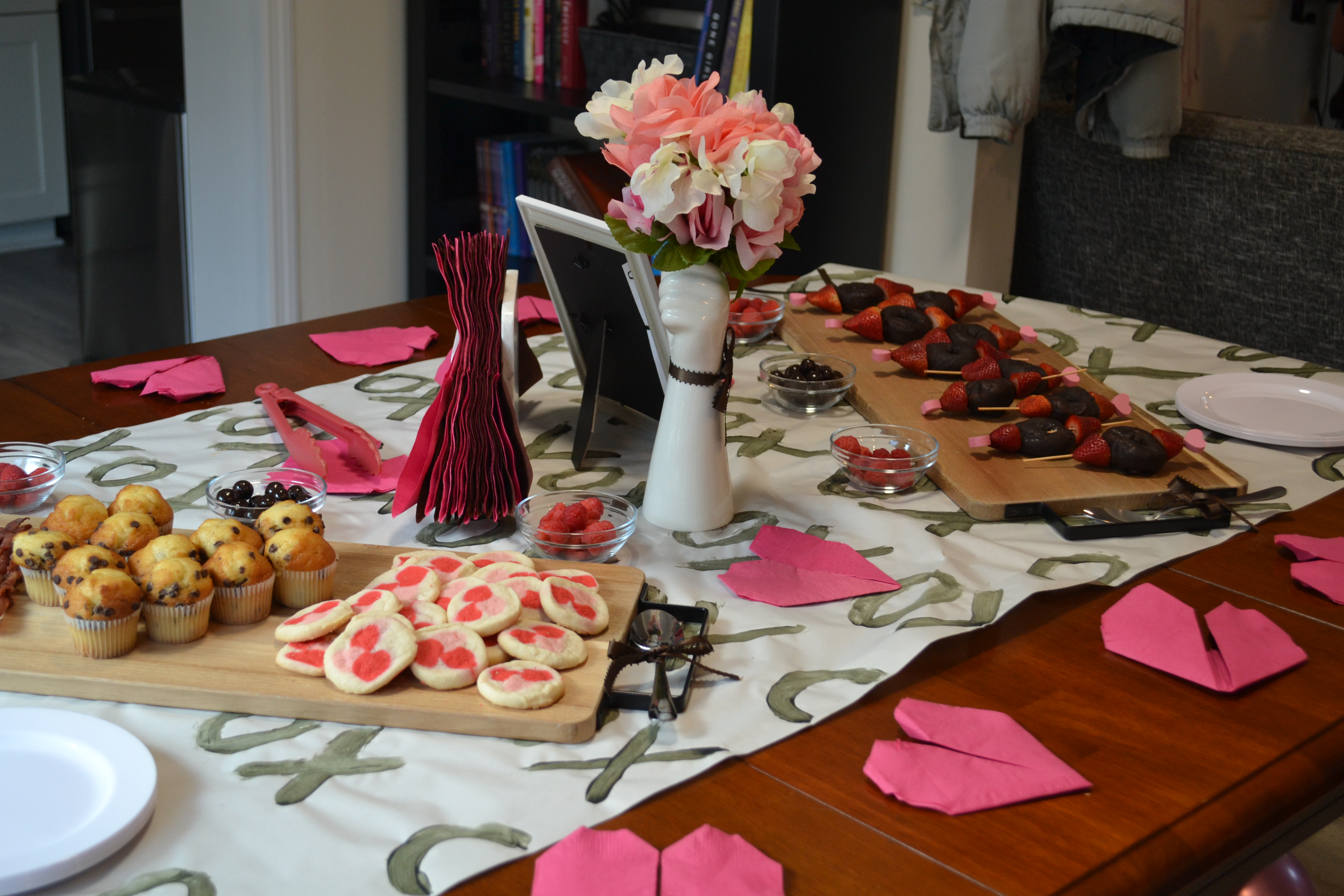 valentine's day brunch table of bacon, muffins, and cookies