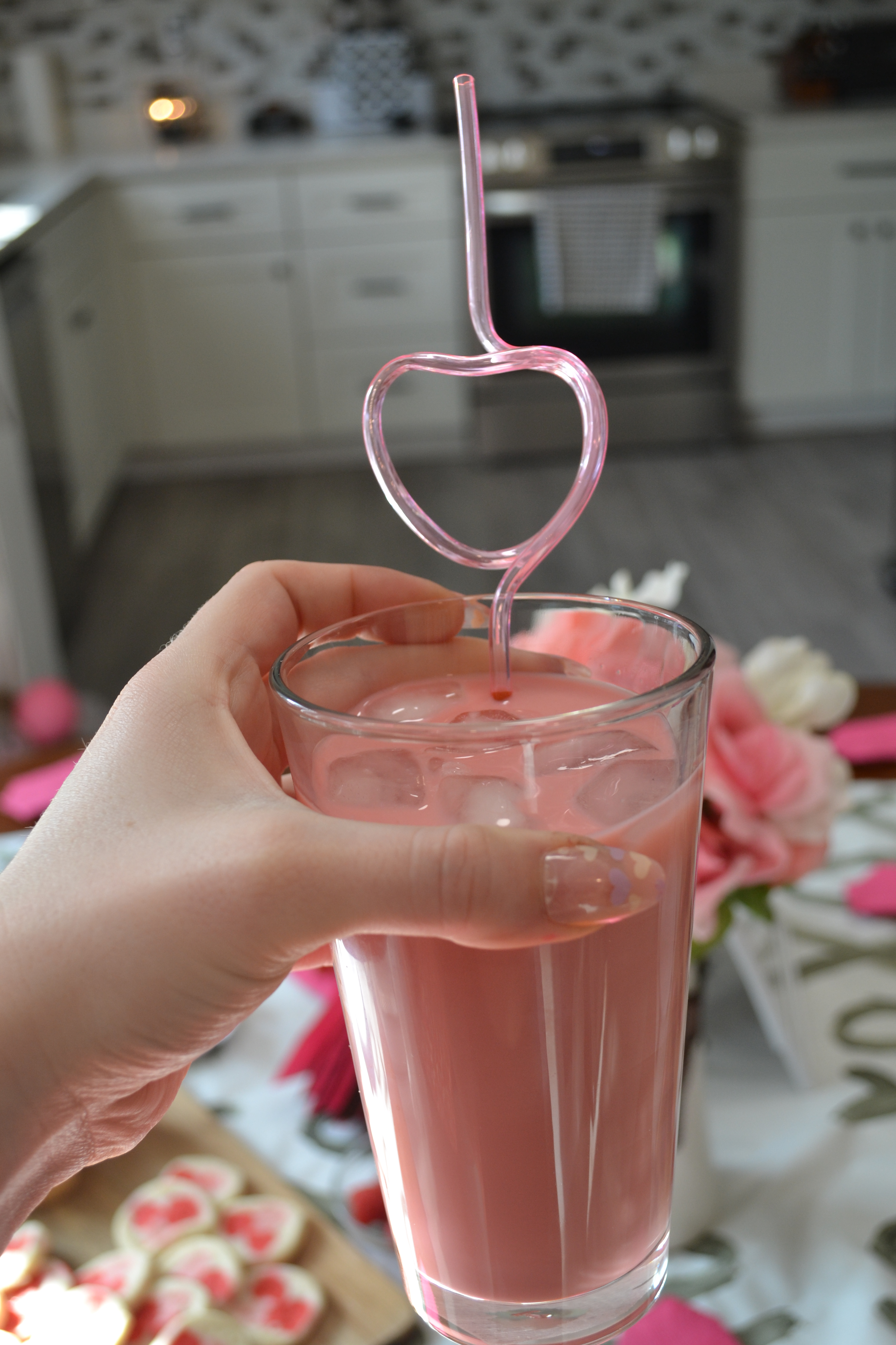 pink iced coffee in a clear cup with a pink heart curly straw