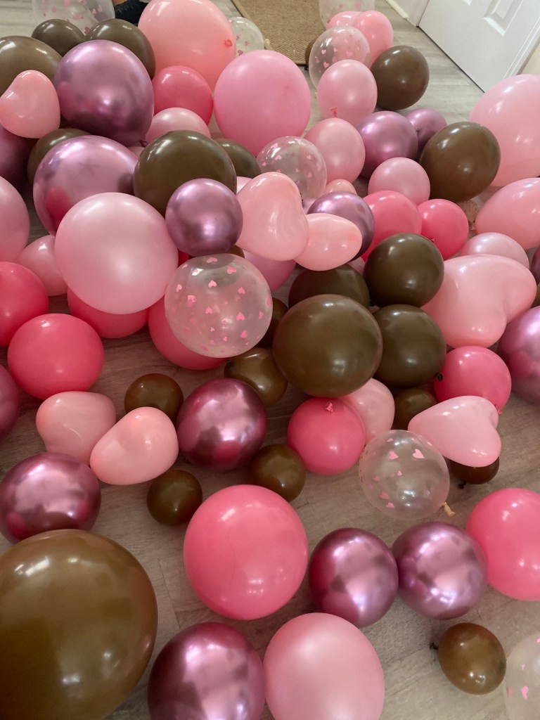 pile of loose, tied balloons on the floor for a valentine's day balloon garland.